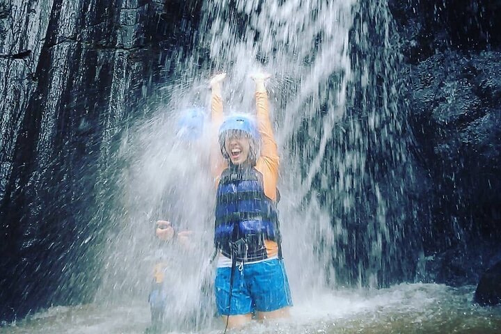 Guest standing under a waterfall during the Telaga Waja rafting stop